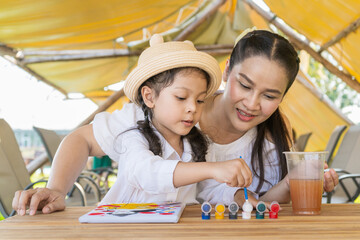 The Asian mother and daughter do a happy painting activity together.