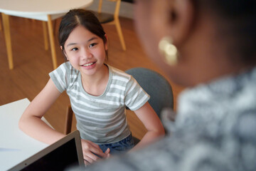 An Asian girl student talks with an African woman teacher while learning science in an...