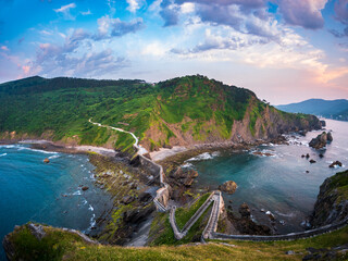 Sunset behind Gaztelugatxe Basque Country Spain winding stone bridge climbing rocky islet toward...