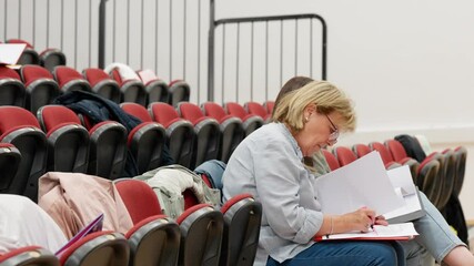 Mature students sitting together taking notes in lecture hall setting - Powered by Adobe