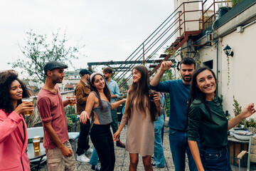 Friends enjoying drinks and dancing at rooftop party