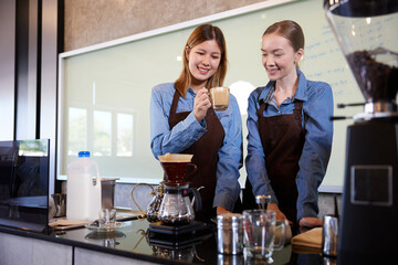 young barista woman making fresh coffee from machine and checking quality in the cafe
