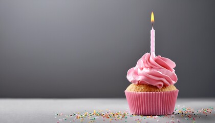 pink birthday cupcake with candle over grey background