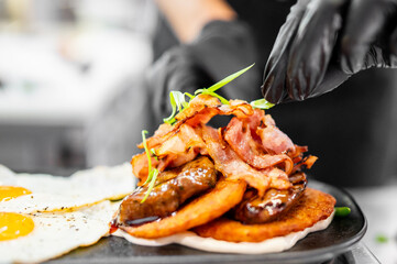 Close-up of traditional breakfast with sunny-side-up eggs, crispy bacon, sausages, and hash browns,...
