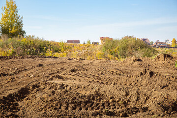 Empty land plot with tire prints prepared for new housing in rural area. Clearing and leveling of...
