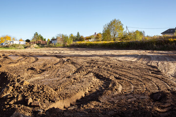 Empty land plot with tire prints prepared for new housing in rural area. Clearing and leveling of...