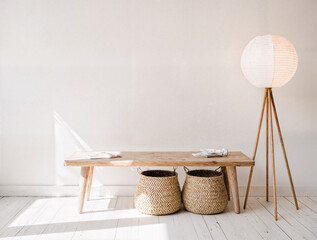 A low wooden bench with a woven basket beneath a floor lamp made of rice paper.