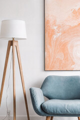 Living room interior with light oak tripod floor lamp, soft blue retro lounge chair and large abstract canvas