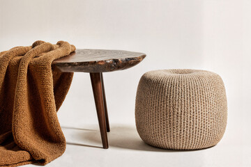 A dark walnut coffee table with organic edges is paired with a bouclé pouf and textured earth tones