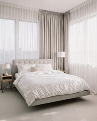 A tranquil and minimal bedroom interior with a low platform bed, crisp white linen bedding and a single floating bed.
