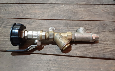 Detailed view of a brass valve and pipe assembly on wooden surface during evening hours of home...