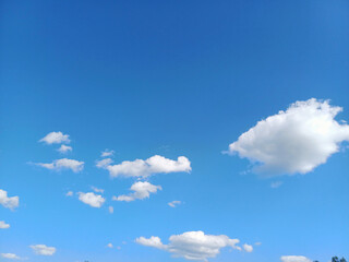 Bright blue sky with fluffy white clouds scattered throughout during a sunny day in a serene...