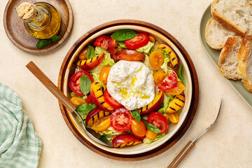 Summer salad with grilled peaches, tomatoes and burrata cheese, dressed with olive oil. Bread. Top view.