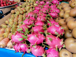 Vibrant display of exotic fruits including dragon fruit and pears at a bustling market