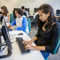 Teenage Students: Computer Studies. A female pupil working on a computer in a technology school class. From a series of high school education related images.