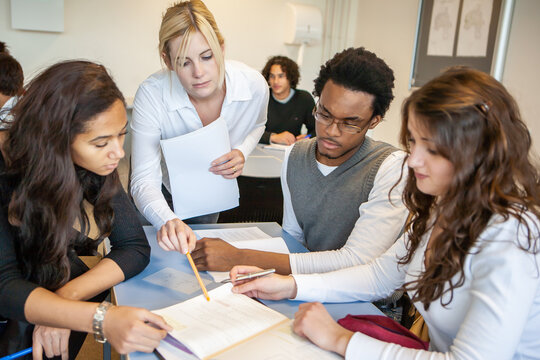 Teenage Students: Teachng Advice. A group of students working together on a group project with a little support from their teacher. From a series of related images.