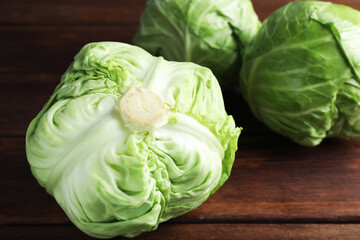 Fototapeta premium Fresh whole cabbages on wooden table, closeup