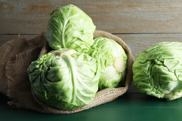 Fresh whole cabbages on green wooden table, closeup