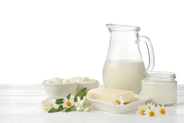 Different fresh dairy products and flowers on wooden table against white background