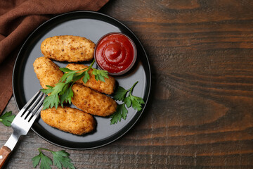Tasty fried croquettes, parsley and sauce on wooden table, flat lay. Space for text