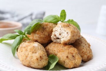 Tasty fried croquettes and basil on table, closeup