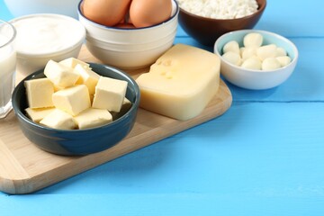 Different dairy products and eggs on light blue wooden table, closeup. Space for text