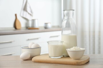 Different dairy products and eggs on wooden table in kitchen
