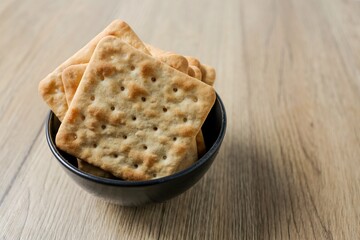Cracker in a black bowl on wooden background table