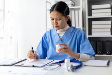 Female doctor reading and writing prescriptions in hospital office. The doctor is calculating the...