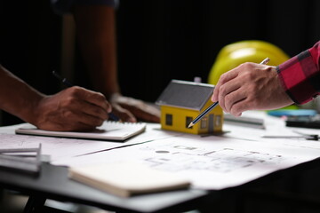 Architect discussing project using model house and blueprint. Architects discussing building plans...