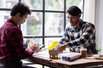 Architect using calculator calculating construction costs on blueprint. Architects collaborating at...