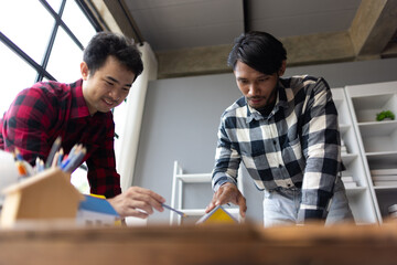 Architect working on model house project on desk. Two young male architects are completely...