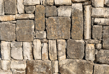 Textured stone wall composed of various sizes and shapes of natural stones in earthy tones
