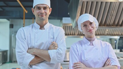 Portrait of man and woman chefs standing with arms crossed in the kitchen