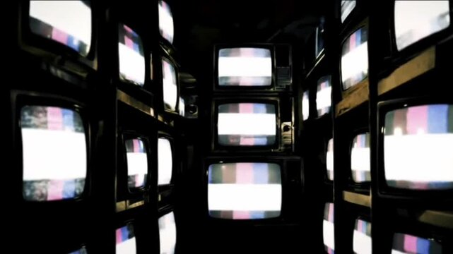 The camera dolly-zooms slowly through a narrow aisle of old televisions stacked on shelves, some screens flickering randomly.