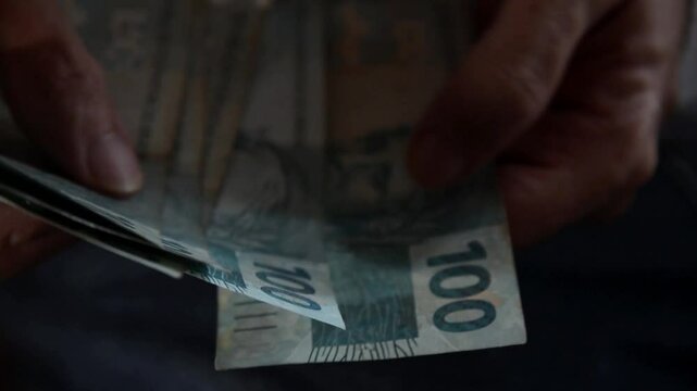 Counting Brazilian money R$100 reais notes. Concept of economy, debts, purchases, trade and payment.