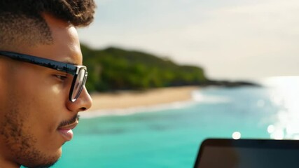 Young freelancer working with laptop while sitting on the beach of the tropical island. The young freelancer finds joy in the tropical setting while staying focused on his projects.