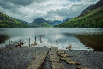 A peaceful view of Buttermere Lake from its north-side beach, captured on an overcast summer day