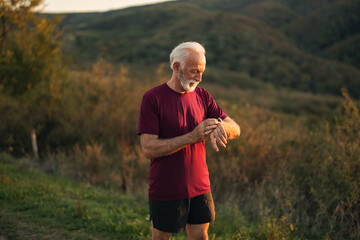 Senior Man Checking Fitness Watch in Outdoor Scenic Landscape