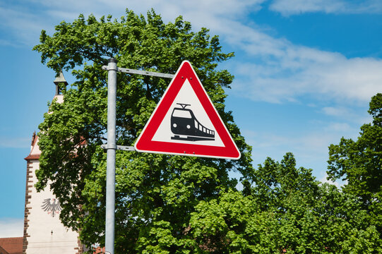 A triangular sign with a red border and white background indicates the proximity of a railroad crossing. 