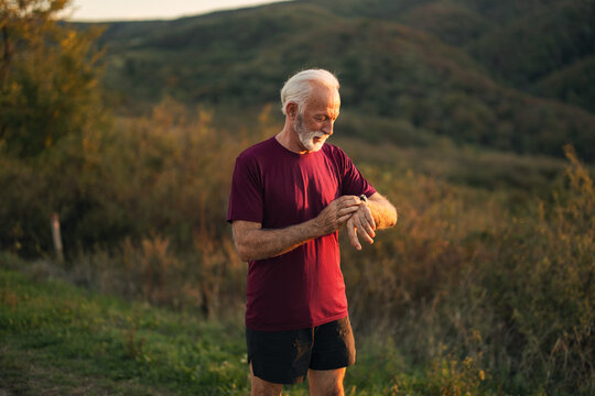 Senior Man Checking Fitness Watch in Outdoor Scenic Landscape