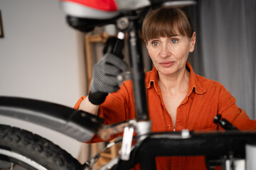 Portrait of concentrated female mechanic repairing bicycle at home in room