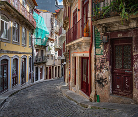 A narrow and hilly street in the old town of Porto.  The  buildings are rundown and covered in graffiti.