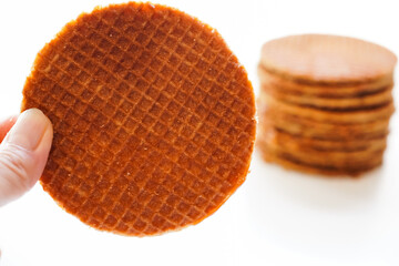 Closeup of woman  holding  stroopwafel  (Dutch caramel waffle)  on white background 
