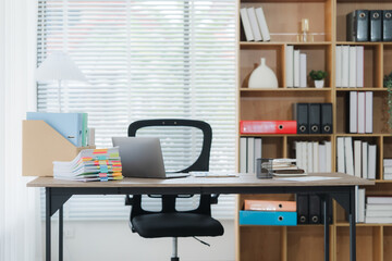 Serene Workspace: An empty office with desk, laptop, chair, and bookshelves set in a minimalist...