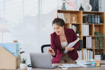 Virtual Collaboration: An engaging young woman in a modern office space, communicating with colleagues via laptop, holding document, showcasing the power of remote connectivity and teamwork.
