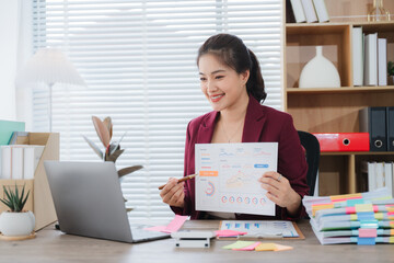 Online Business Presentation: A smiling businesswoman confidently presents a business chart during a video conference, showcasing professionalism and expertise in a modern office setting. 