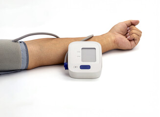 Digital blood pressure monitor is wrapped around arm, displaying modern medical device used for measuring blood pressure. setup is on clean, white background, emphasizing equipment functionality