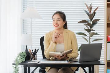 Daydreaming at Desk: A focused businesswoman finds a moment to pause and reflect. Natural light...