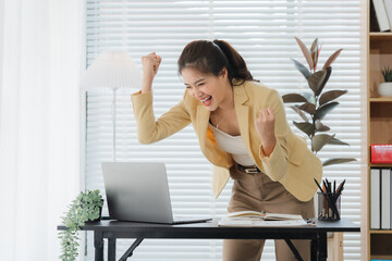 Triumphant Moment in Office: A woman celebrates a business achievement with joyful expression, the...